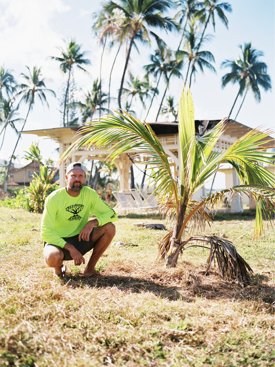 Maui fires in Lahaina featuring Kai McPhee sits next to the surviving tree he planted on his son’s first birthday